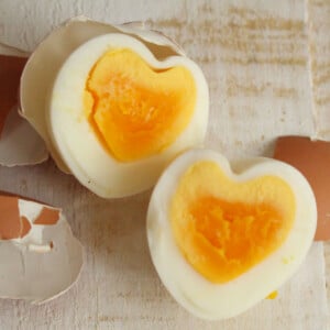 Heart shaped egg halves next to egg shelves.