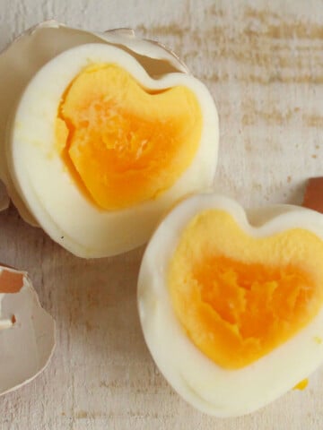 Heart shaped egg halves next to egg shelves.