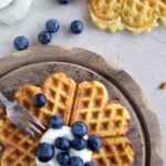 heart-shaped waffles on a table decorated with blueberries and a fork
