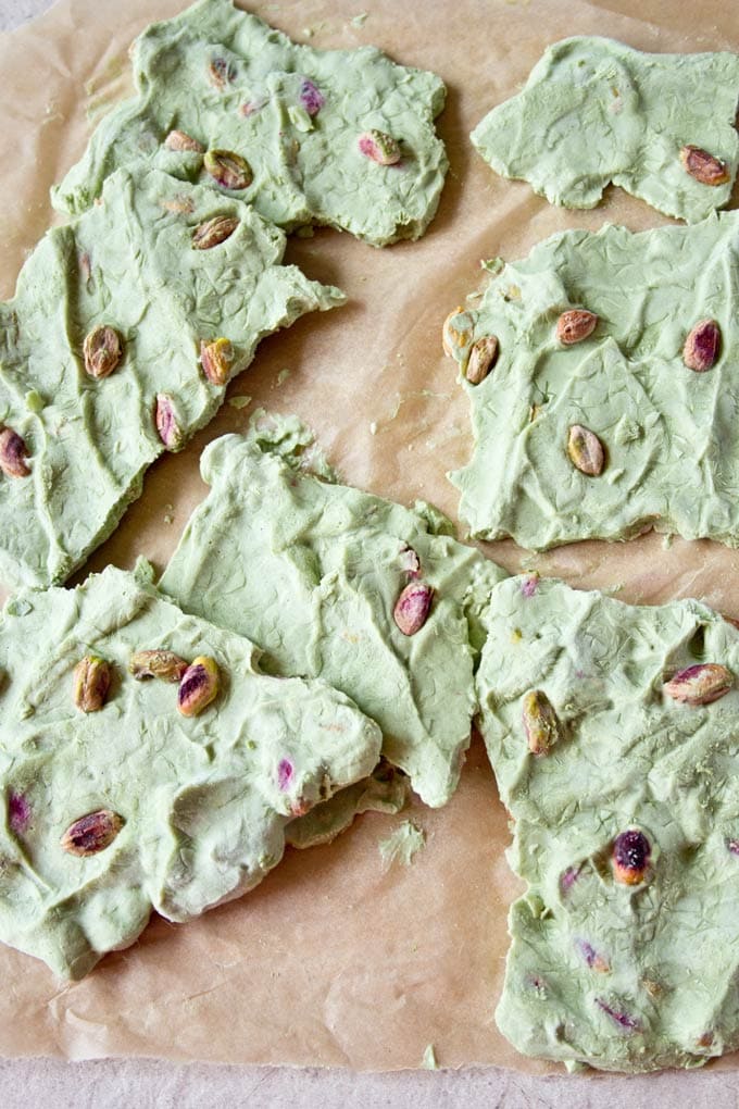 pieces of matcha yogurt bark scattered on parchment paper