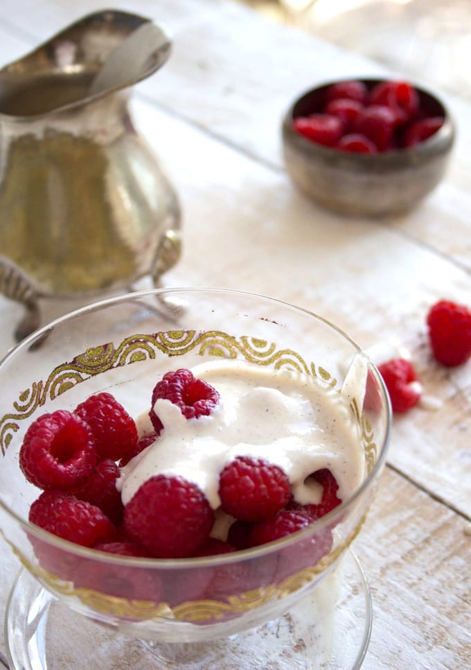 raspberries in a glass dessert bowl topped with cashew vanilla sauce