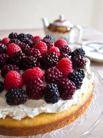 A sugar free almond flour cake decorated with mascarpone frosting and topped with berries