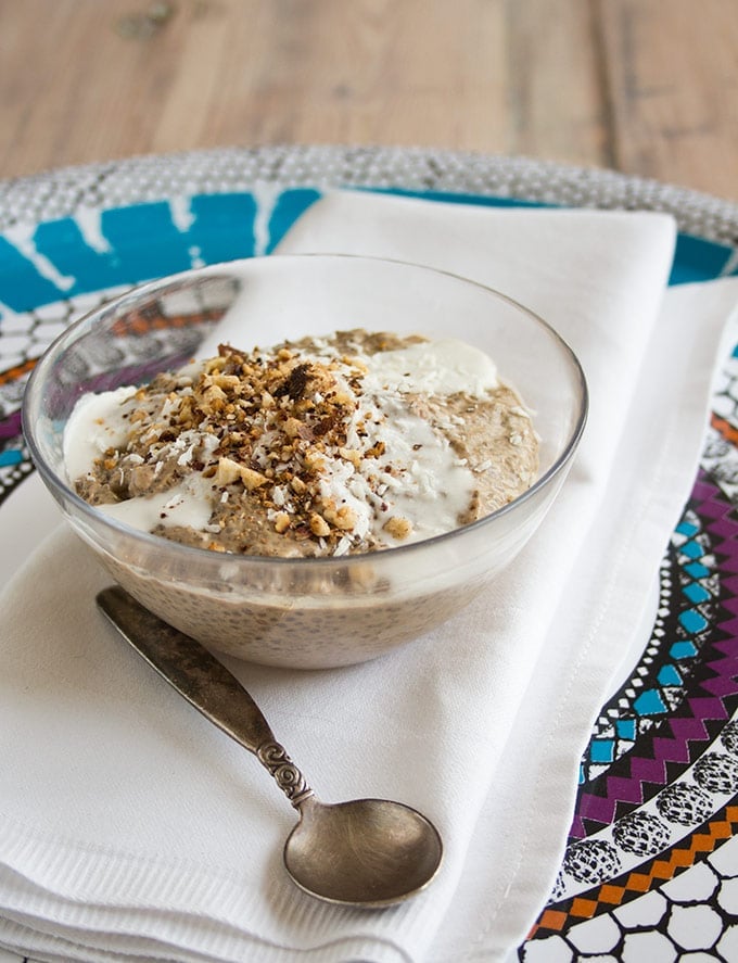 a portion of coffee chia pudding topped with crushed nuts and coconut milk 