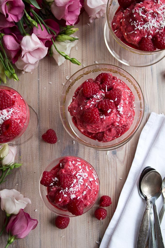 raspberry frozen yogurt in glass serving bowls on a table with pink roses
