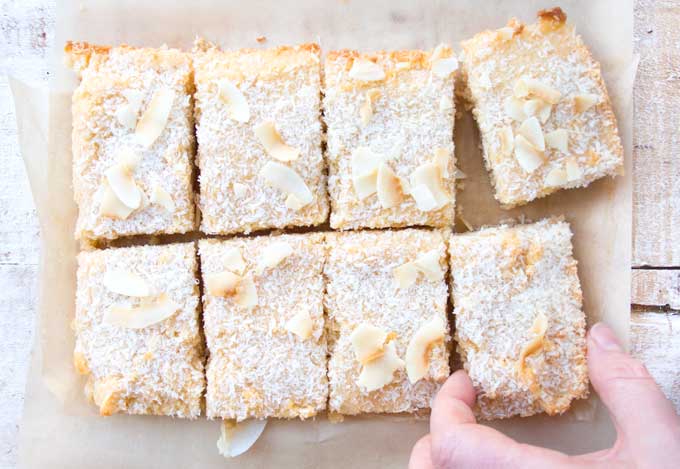slices of Keto blondies on a tabel with a hand taking one of the blondies