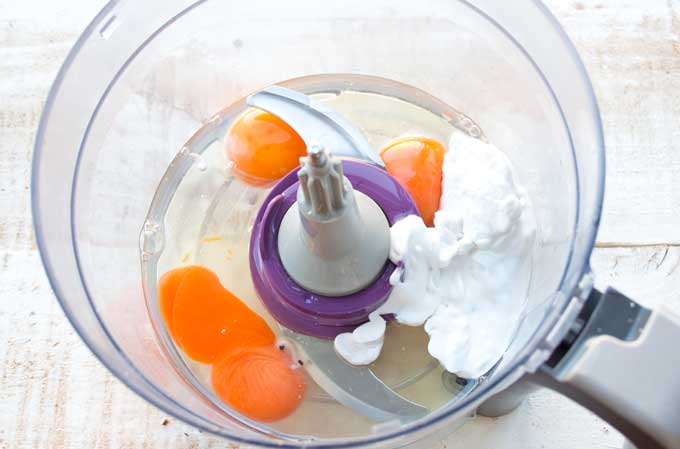a food processor bowl with eggs, coconut oil and coconut cream