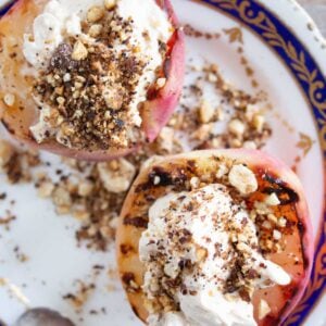 two grilled peach halves topped with mascarpone and hazelnuts