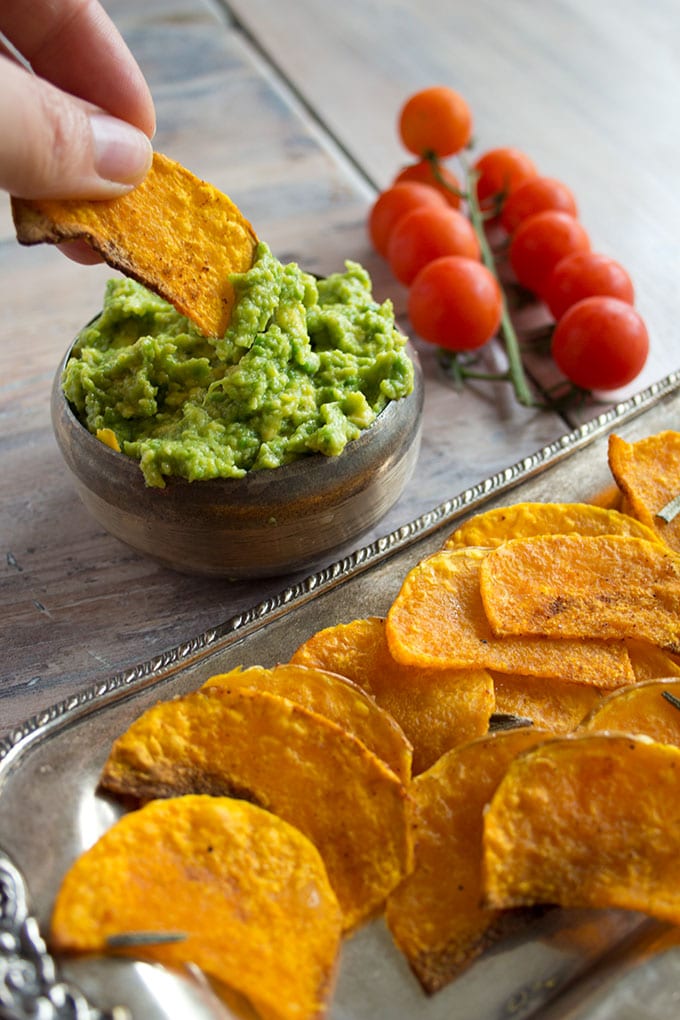 hand dipping butternut squash chips into guacamole