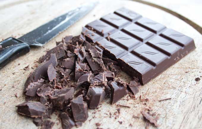 A bar of half-chopped dark chocolate with a knife 