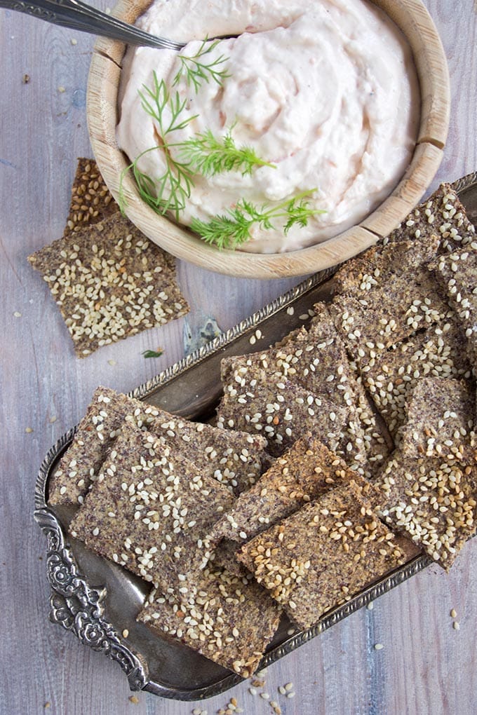 a tray with sesame flaxseed crackers and a dip
