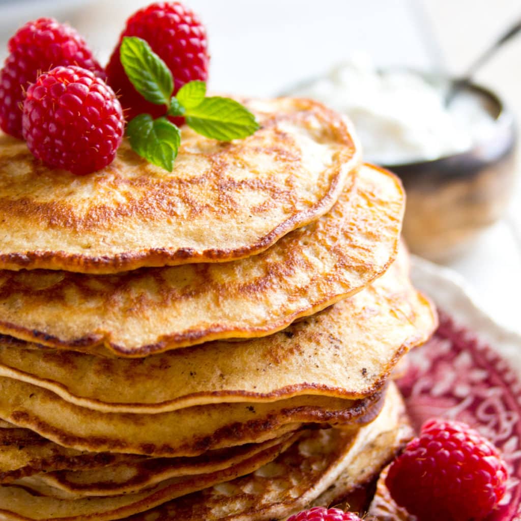 a stack of keto pancakes made with almond flour and cream cheese, decorated with raspberries