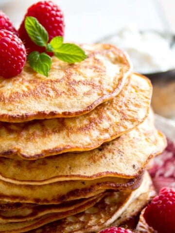 a stack of keto pancakes made with almond flour and cream cheese, decorated with raspberries