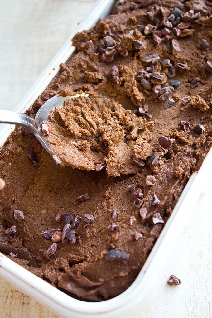 A spoon taking chocolate avodaco ice cream out of a container