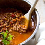 healthy Bolognese sauce with a wooden spoon in a pot