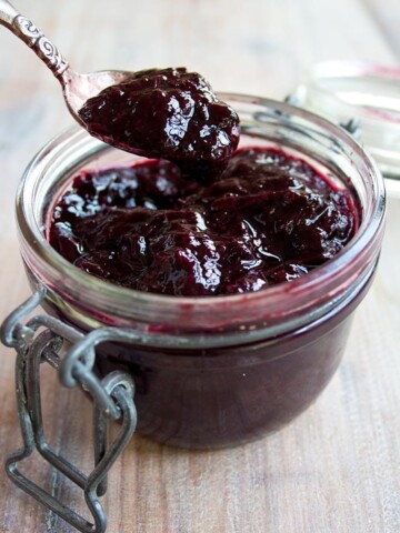 An open jar of sugar free blueberry jam with a spoon