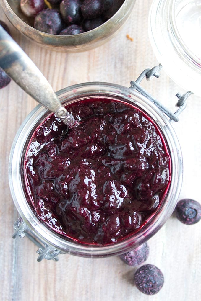 A glass jar of sugar free blueberry jam with a spoon