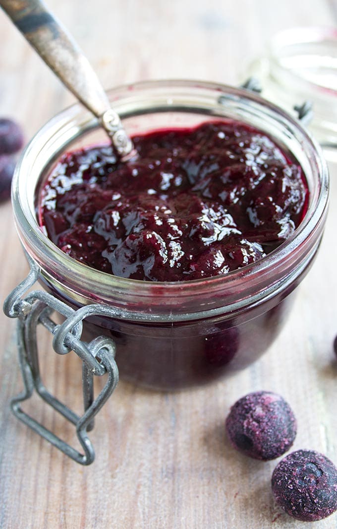 An open jar of sugar free blueberry jam with a spoon
