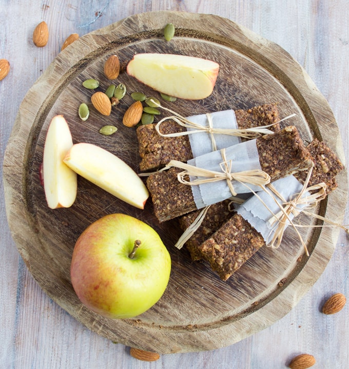 three flapjacks on a board with apple slices and nuts