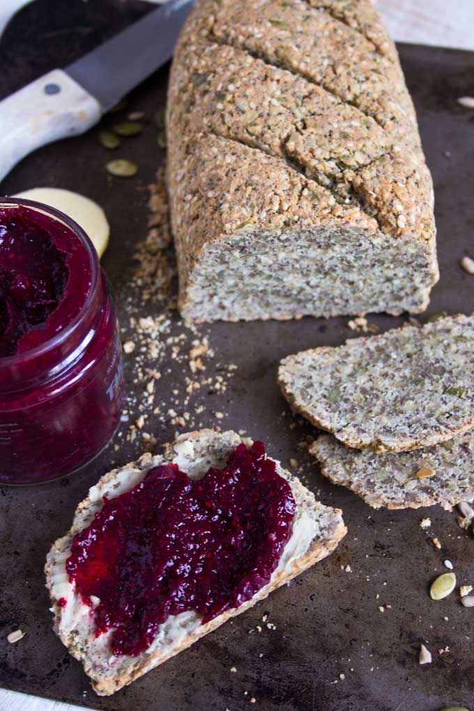  a slice of paleo bread with jam and a loaf of paleo bread
