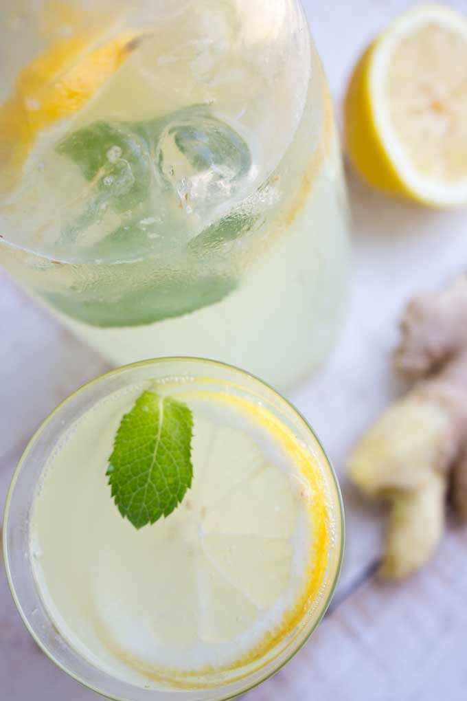 a glass of homemade sugar free ginger ale with ginger and a lemon on the side