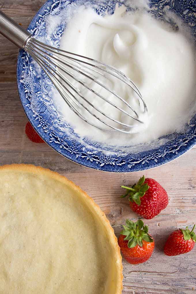 whipping egg whites in a bowl with a whisk for the mascarpone filling and a coconut flour tart base