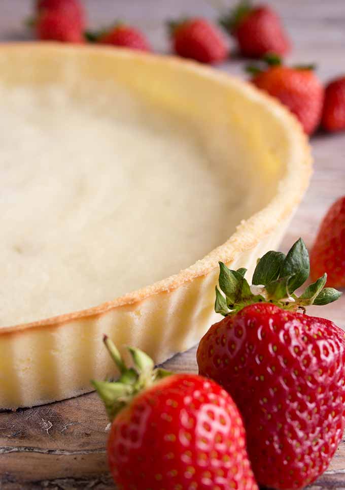 a coconut tart base with strawberries scattered around