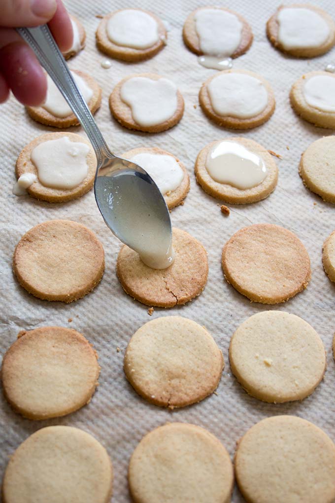 a spoon drizzling coconut glaze on low carb keto shortbread cookies 
