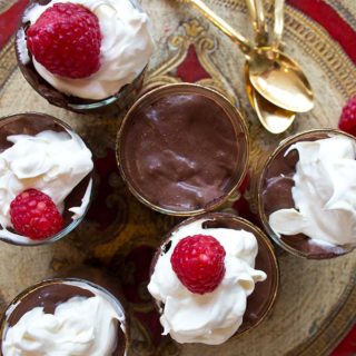 chocolate mouse in glasses topped with cream and raspberries