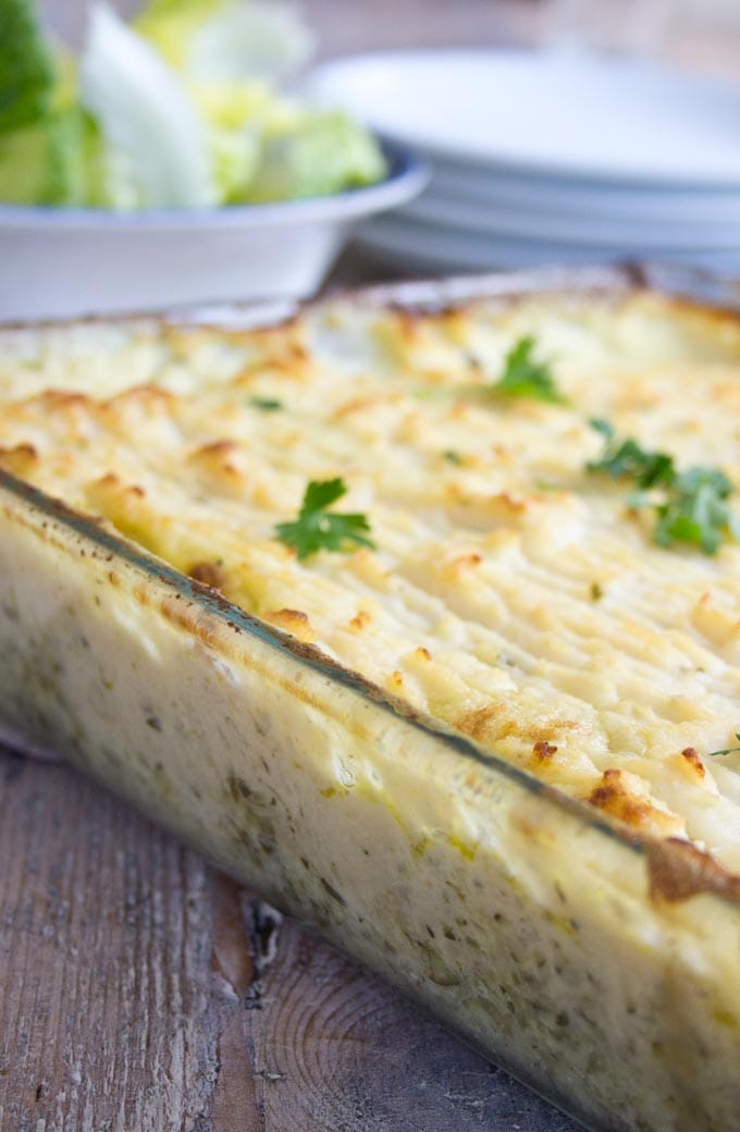 a casserole dish with low carb fish pie and a green salad
