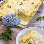serving a portion of keto fish pie on a plate and a casserole of fish pie