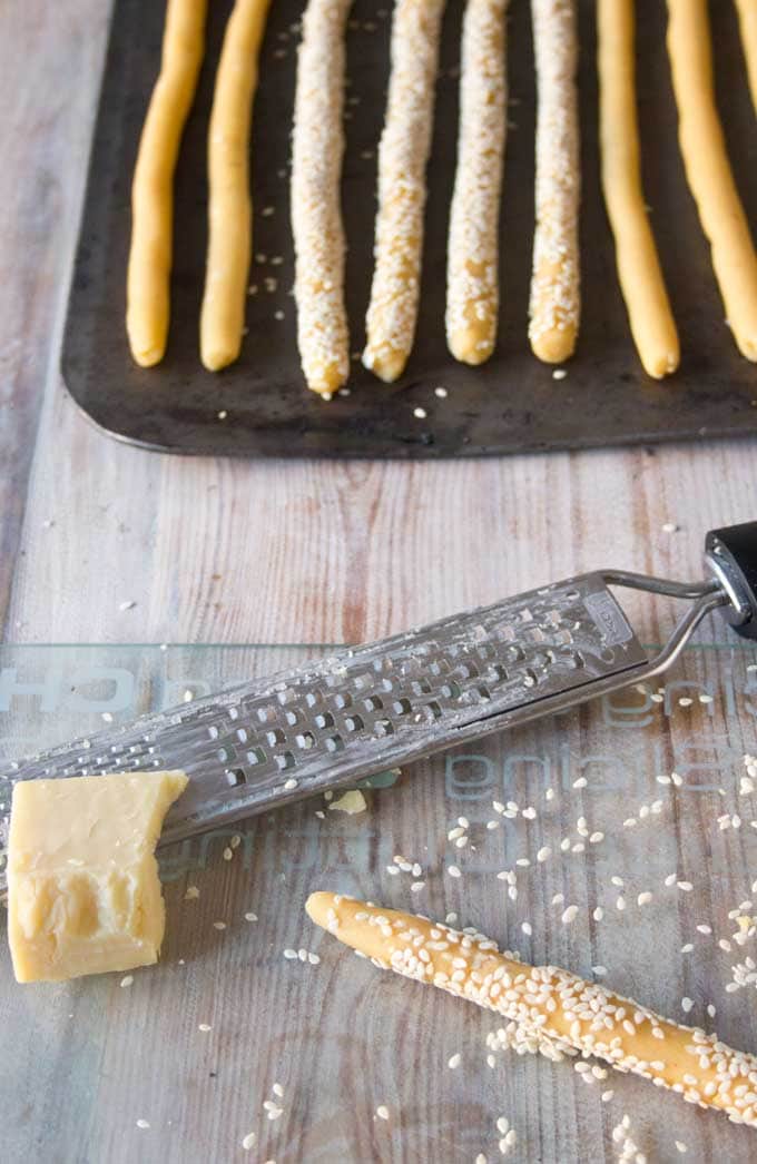 unbaked cheddar breadsticks and a chink of cheddar with a grater