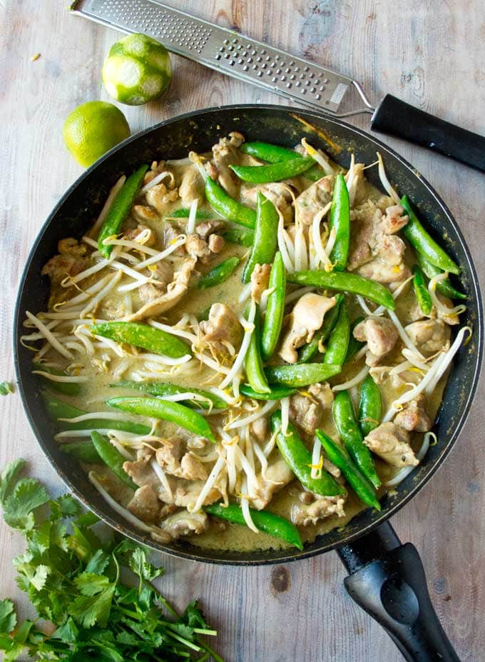 A pan with chicken green curry plus a grater and lime