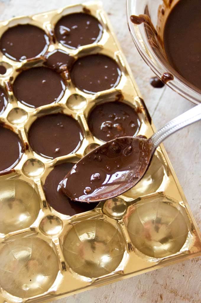 Filling the liquid chocolate mix into a tray mould with a spoon