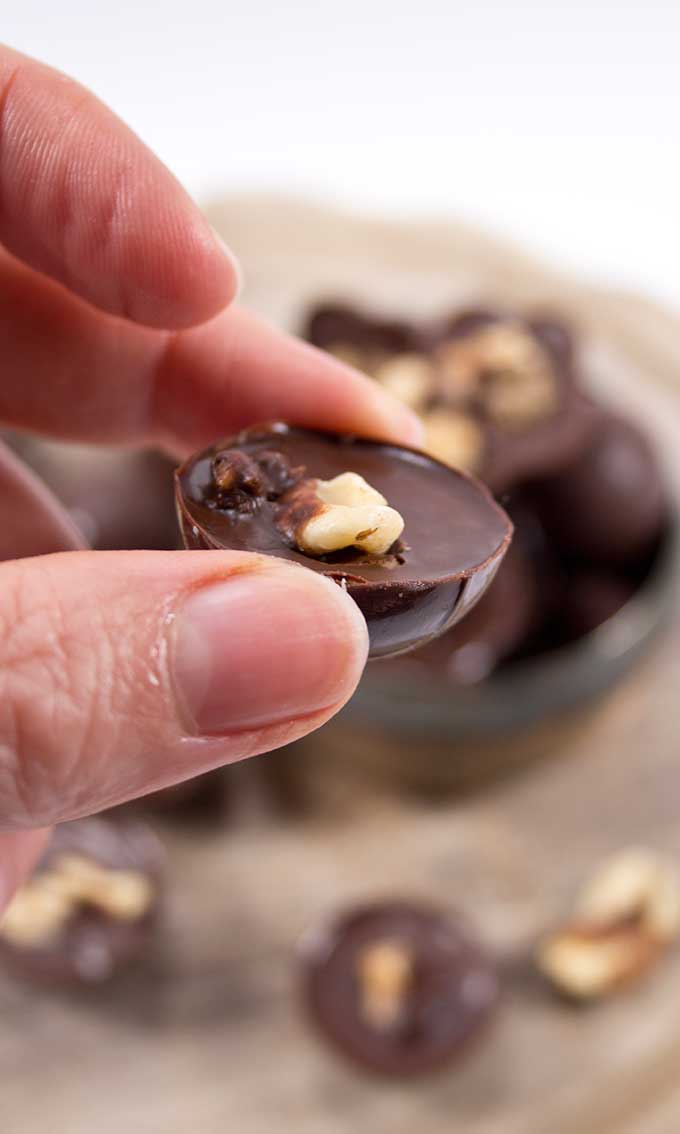 Hand holding a chocolate praline topped with a walnut