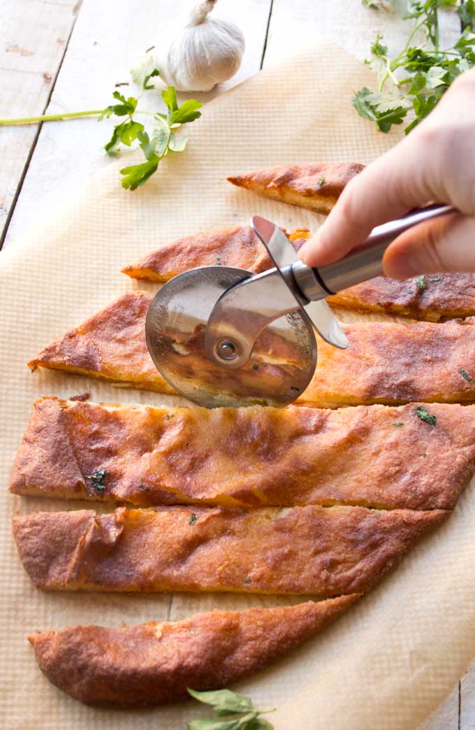 keto garlic bread being sliced with a pizza cutter