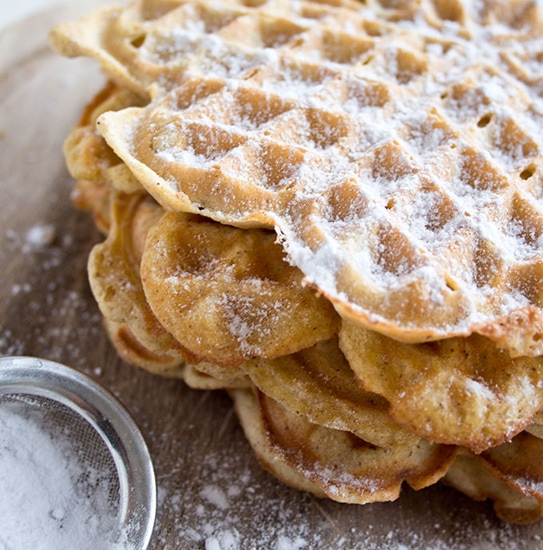 closeup of a stack of heart-shaped waffles dusted with powdered sweetener