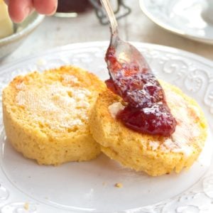 2 keto english muffin slices with butter and a spoon dropping jam onto one slice