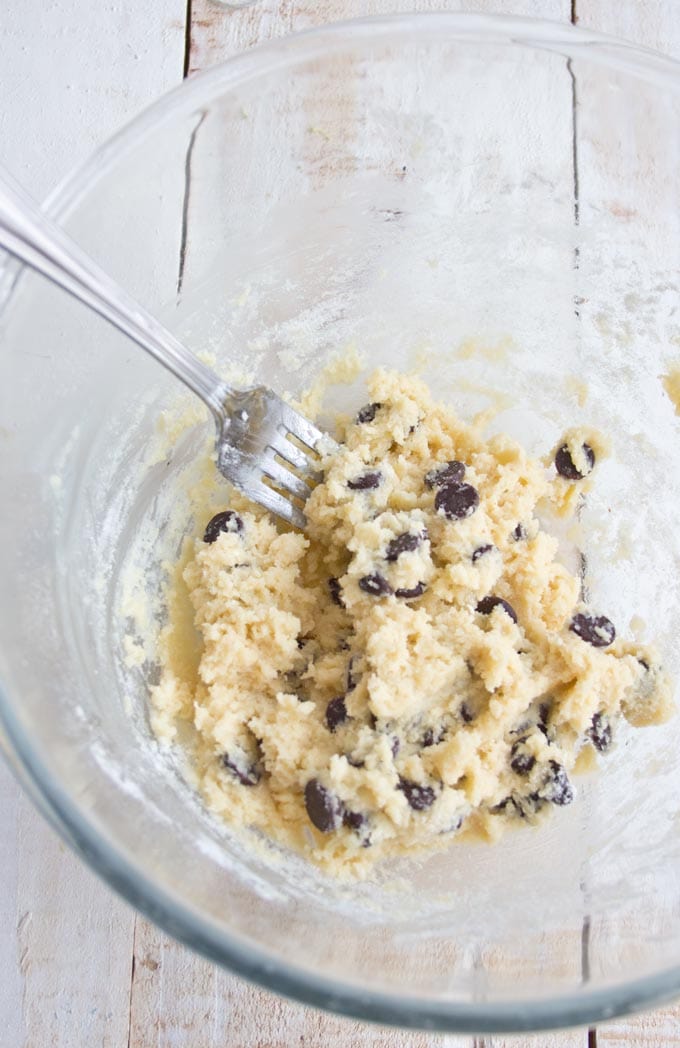 A mixing bowl with cookie dough with a fork