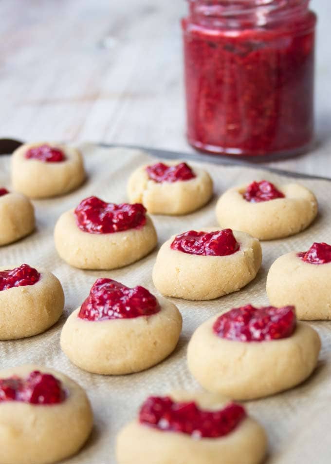 almond flour cookies filled with sugar free raspberry jam on a baking tray