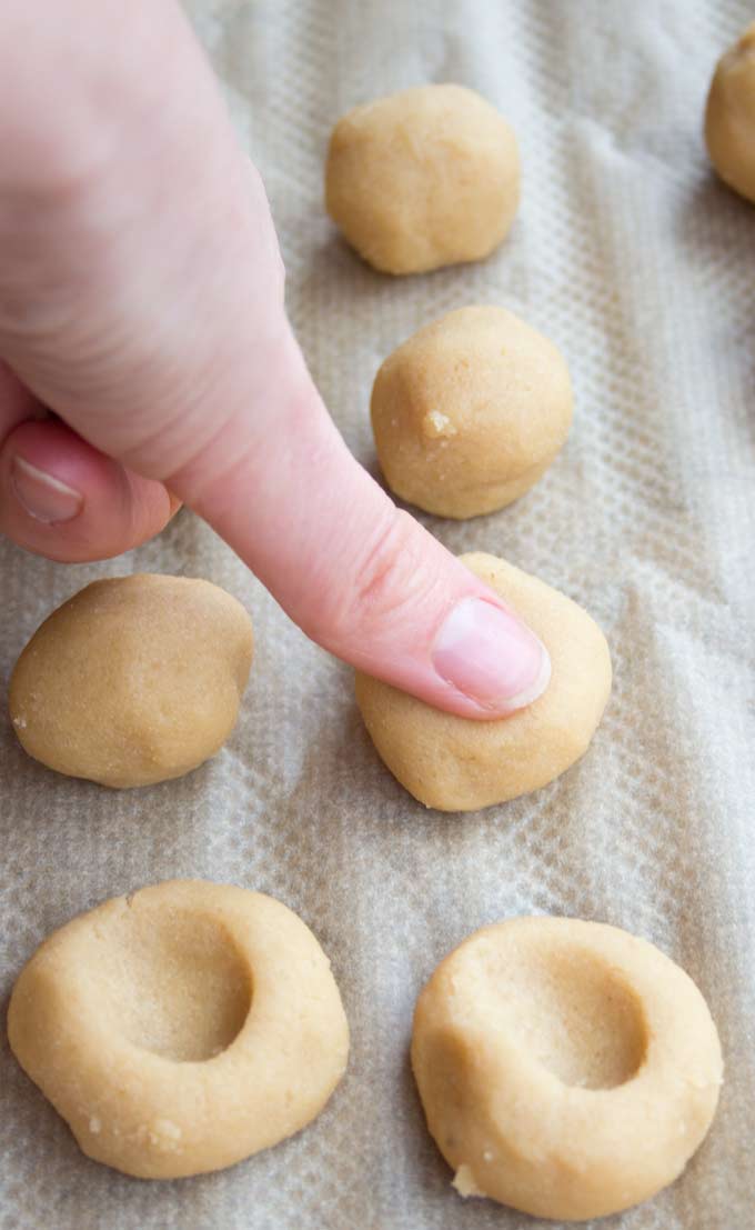 A thumb pressing indents into unbaked low carb cookies