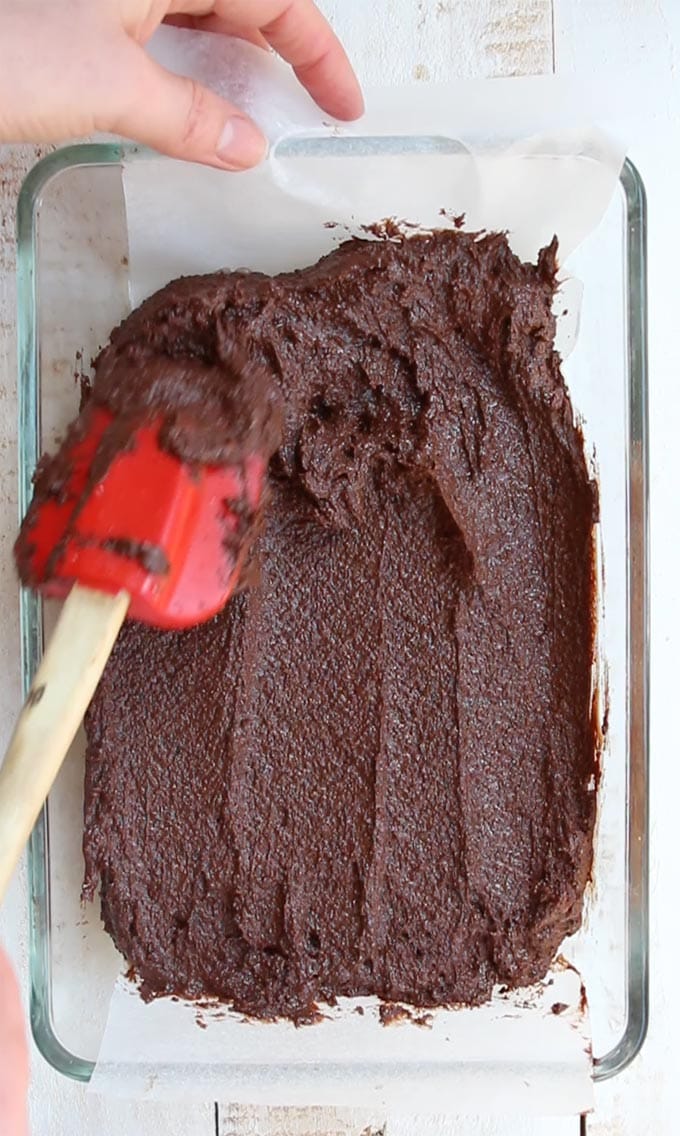 brownie batter distributed in a baking pan with a spatula