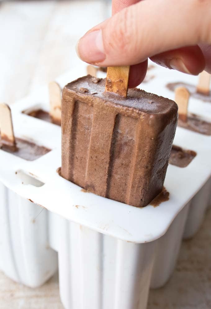 Hand pulling a finished sugar free chocolate popsicle out of a mould