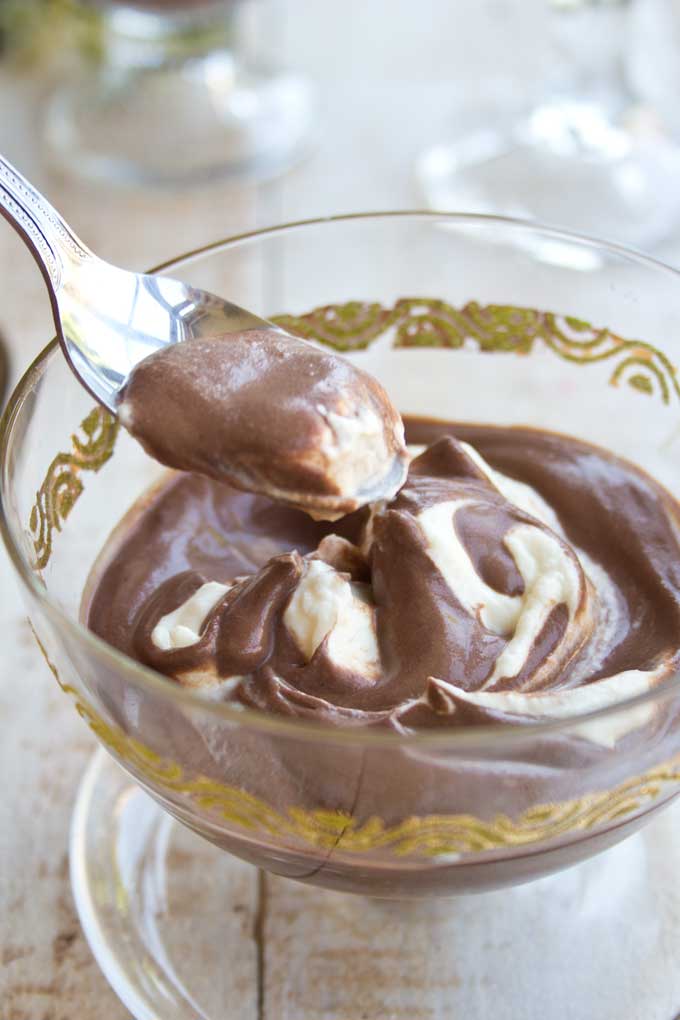 A spoon taking a a spoonful of chocolate mascarpone mousse out of a bowl