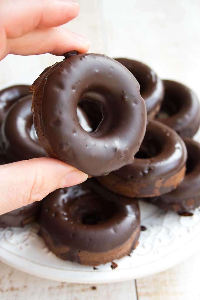 Hand holding a Keto chocolate donut with chocolate glaze 