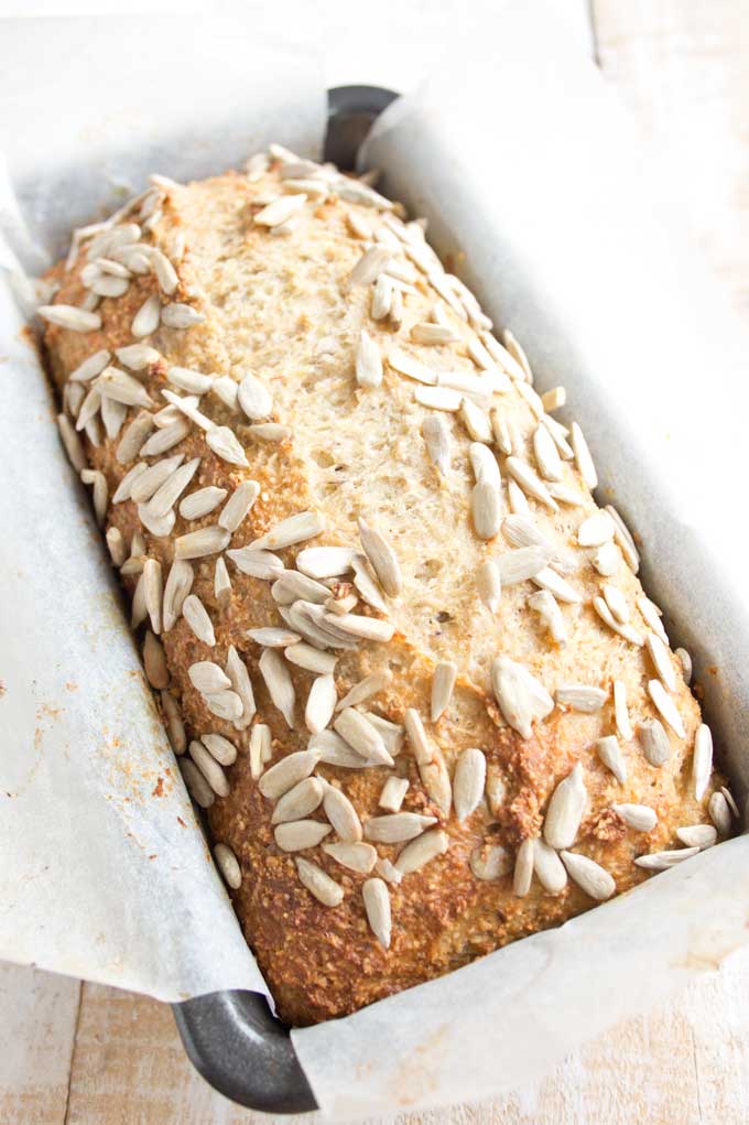 A loaf of chia almond bread inside a lined bread tin straight out of the oven 