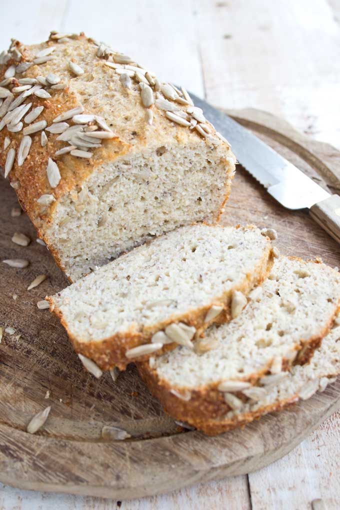 A Cut Loaf of Chia Almond low carb Bread Topped with Sunflower Seeds with a Knife on the side