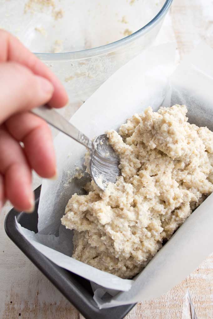 Batter for chia almond low carb bread being filled into a lined bread tin with a spoon