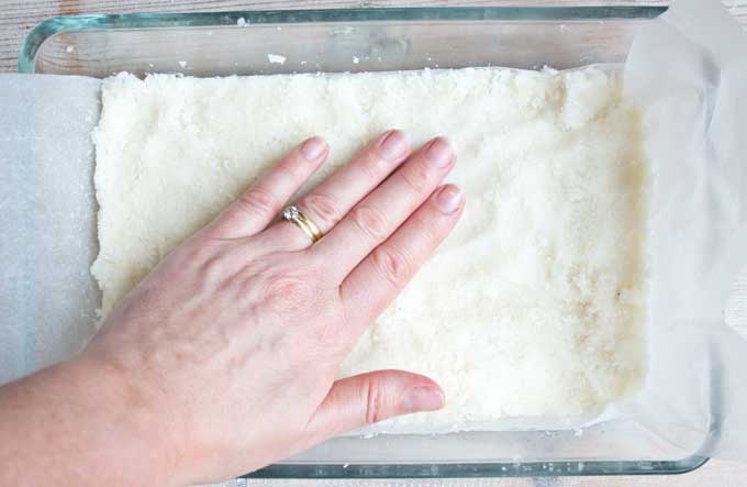 Hand pressing down Keto coconut mix