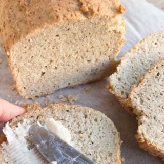 Knife spreading butter on a slice of almond flour bread