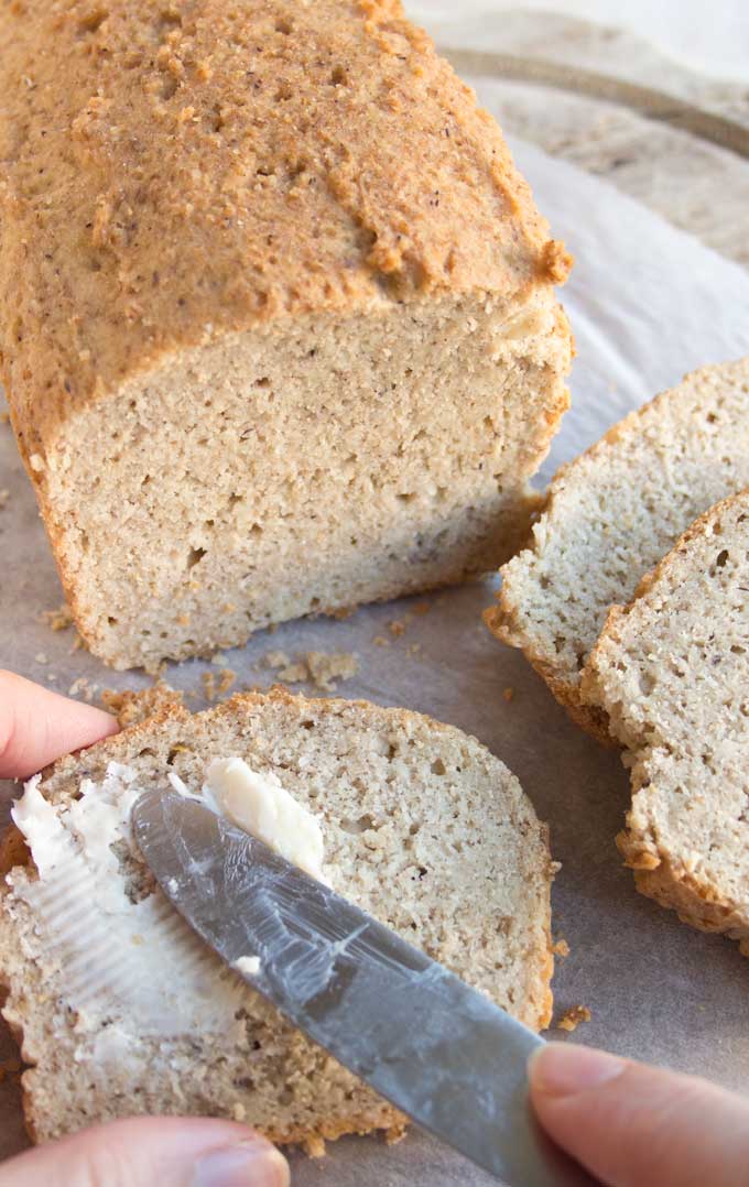 Knife spreading butter on a slice of almond flour bread